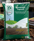 Packs of Somerset Topsoil with a visible Pennys brand logo on a wooden surface.